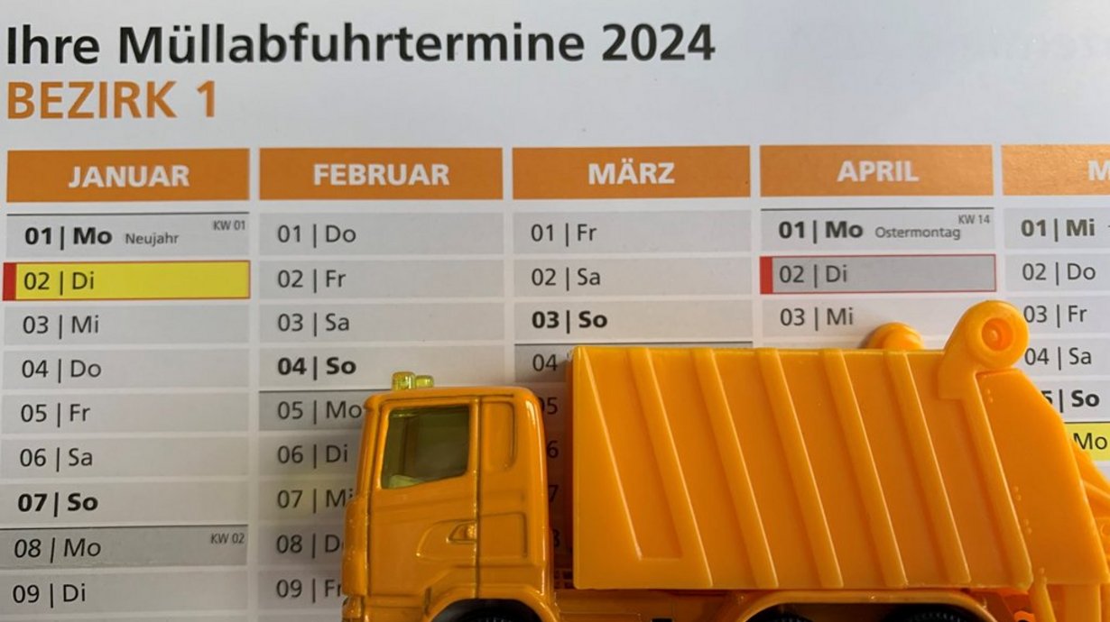 Ein Spielzeug-Müllwagen steht auf einem Müllabfuhrkalender für das Jahr 2024.